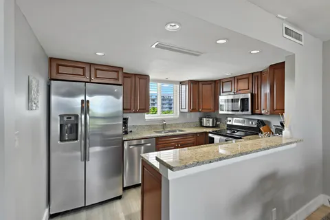 a kitchen with stainless steel appliances granite countertop a refrigerator a sink a stove and oven