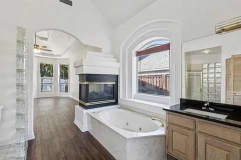 a spacious bathroom with a tub a double vanity sink a window and a mirror