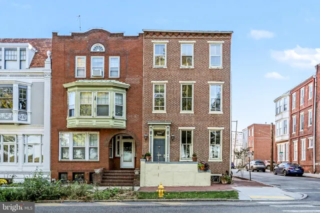 a front view of a brick building next to a yard