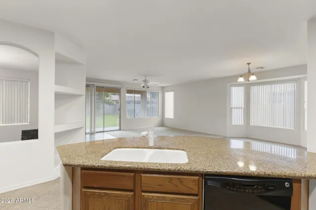 a kitchen with granite countertop a sink a counter top space and cabinets
