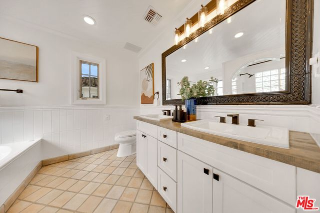 a spacious bathroom with a double vanity sink a mirror and a