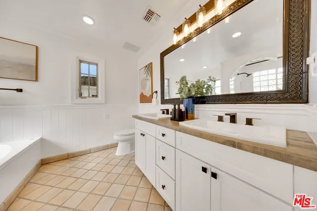 a spacious bathroom with a double vanity sink a mirror and a