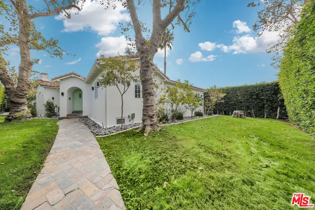 a view of a white house with a yard and table and chairs under large tree