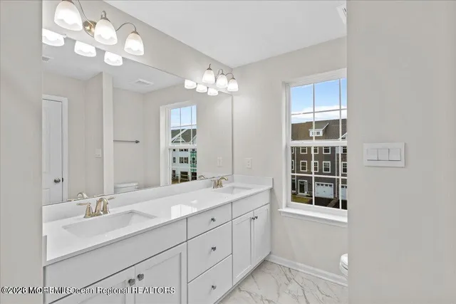 a bathroom with double vanity sink a vanity a lamp and a mirror