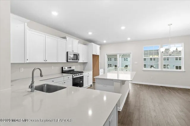 a large kitchen with stainless steel appliances granite countertop a sink a stove and a refrigerator with wooden floors