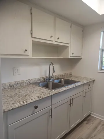 a kitchen with granite countertop white cabinets and a sink