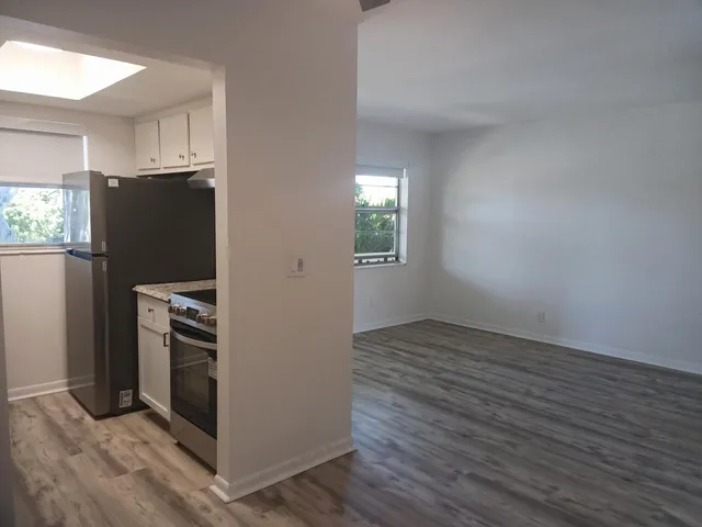 a view of a kitchen with wooden floor electronic appliances and window