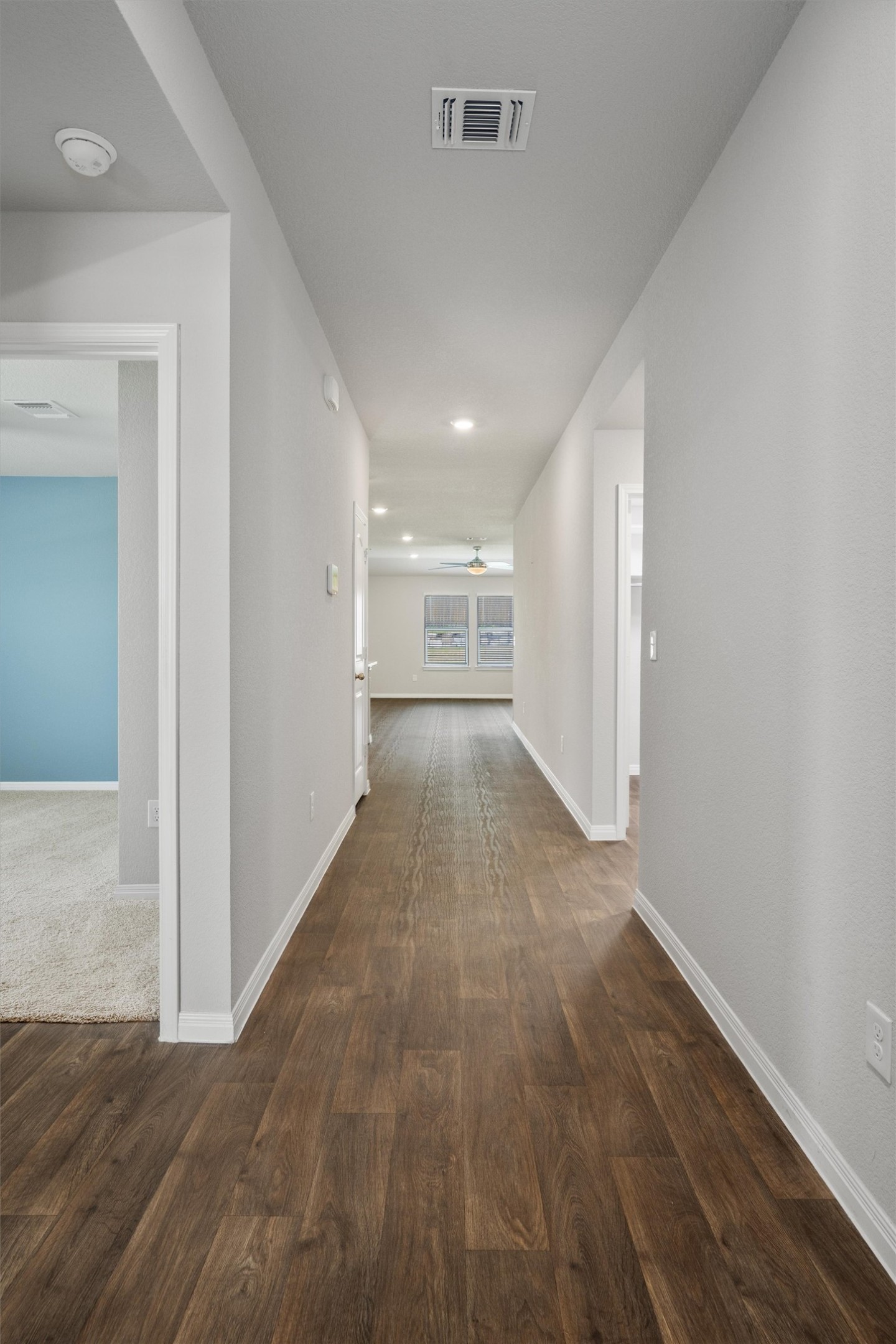 19525 Abigail Fillmore Road Manor, TX 78653 - Photo 12 of 38 A long, inviting hallway offers seamless flow with rich wood flooring leading to sun-filled windows.