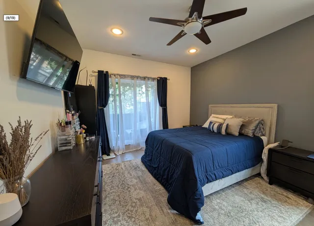 a bedroom with a bed and a flat tv screen on dresser