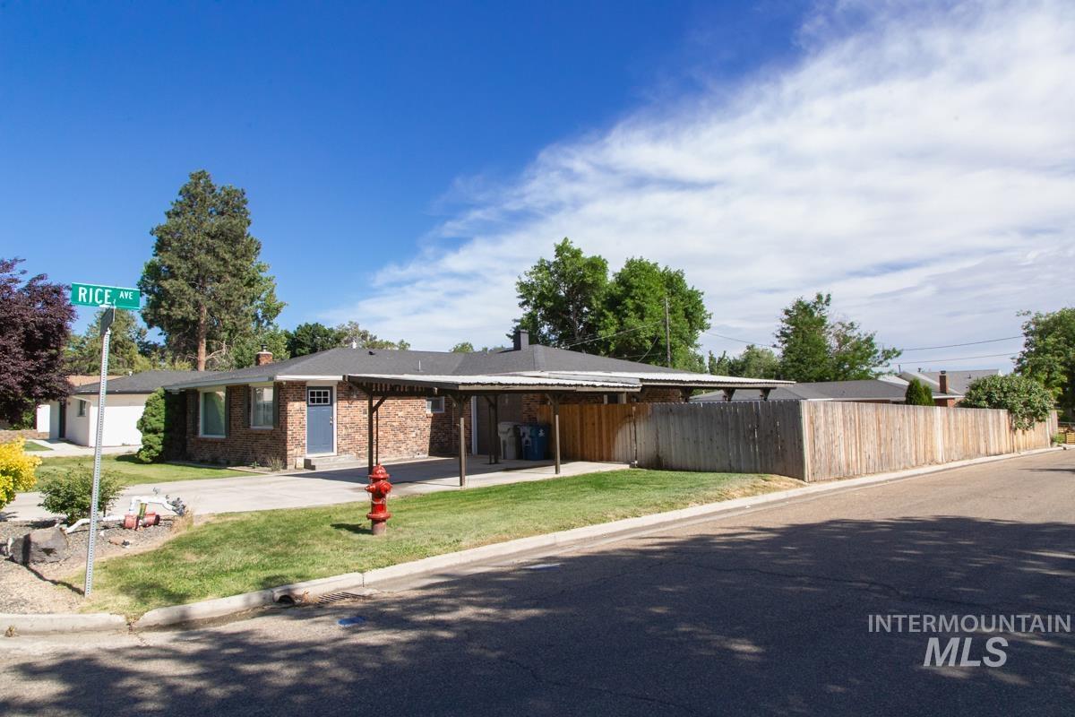 1404 Rochester Street Caldwell, ID 83605 - Photo 2 of 29 Brick exterior residence with a covered carport, mature landscaping, and a wood privacy fence