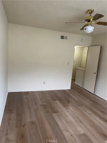 an empty room with wooden floor and fan