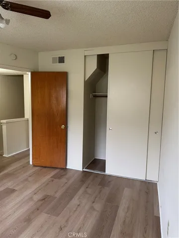 a view of an empty room with wooden floor and closet