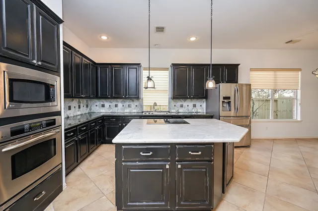 a kitchen with kitchen island granite countertop stainless steel appliances and refrigerator