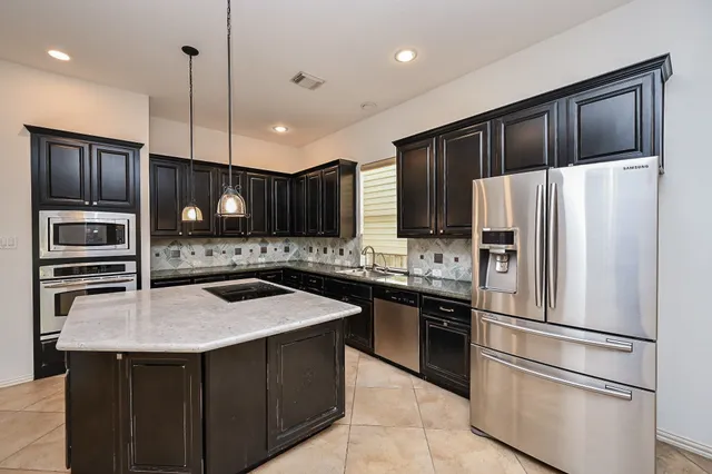 a kitchen with a stove a refrigerator a sink a center island and wooden floor