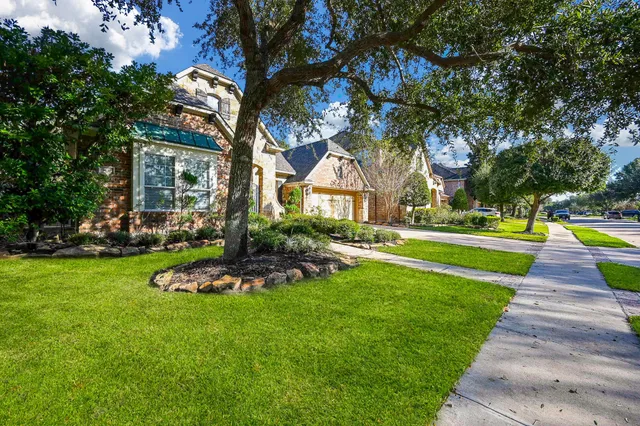 a front view of a house with garden and trees