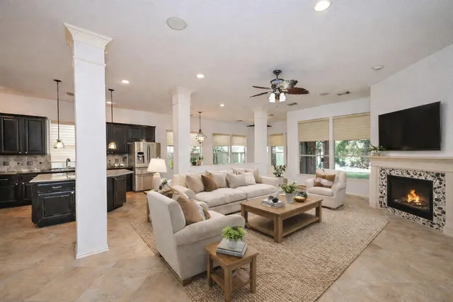 a view of an empty room with kitchen and fireplace