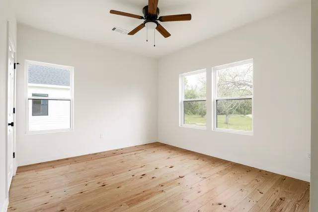 a view of empty room with wooden floor and window