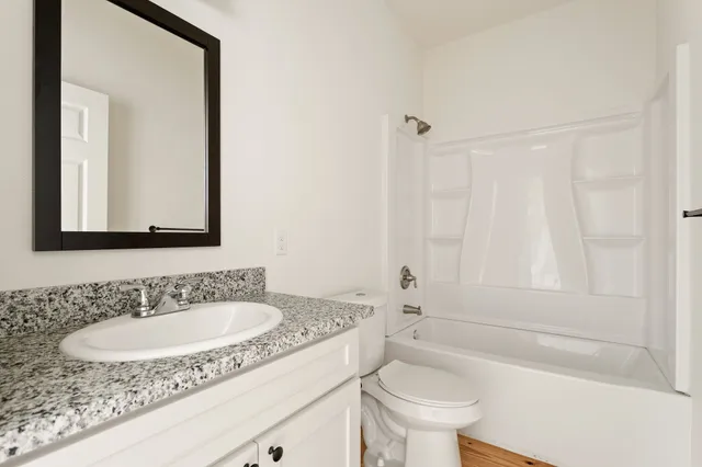 a bathroom with a granite countertop sink toilet and a mirror