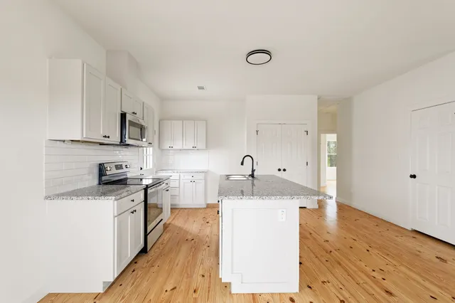 a large kitchen with cabinets wooden floor and stainless steel appliances