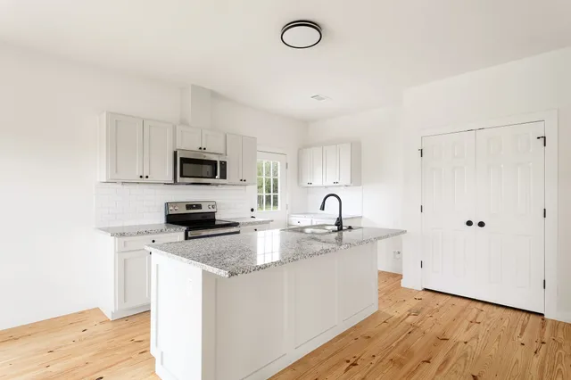 a kitchen with granite countertop a sink a stove a microwave and wooden floor