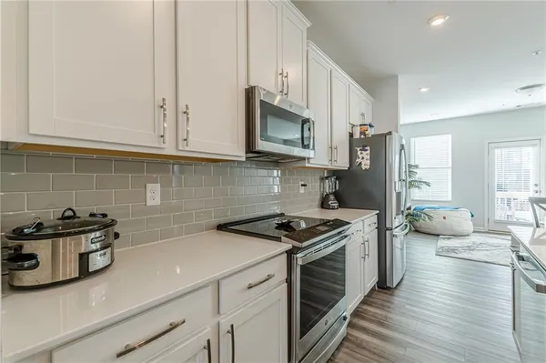a kitchen with stainless steel appliances a stove a sink cabinets and a wooden floor