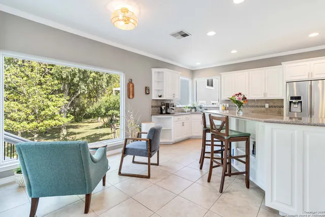 a kitchen with stainless steel appliances granite countertop a table chairs and a refrigerator