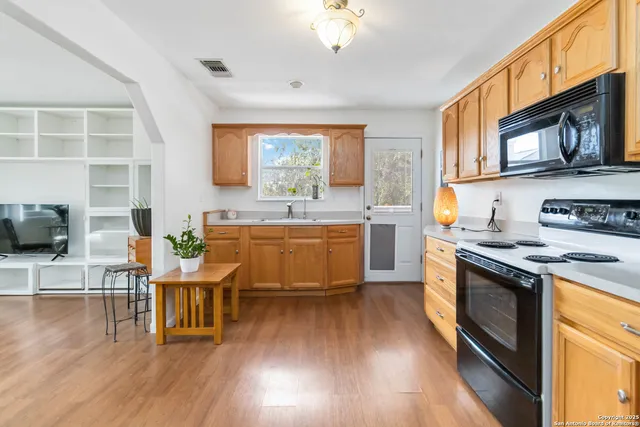 a kitchen with stainless steel appliances granite countertop a stove a sink dishwasher a microwave oven and a dining table with wooden floor