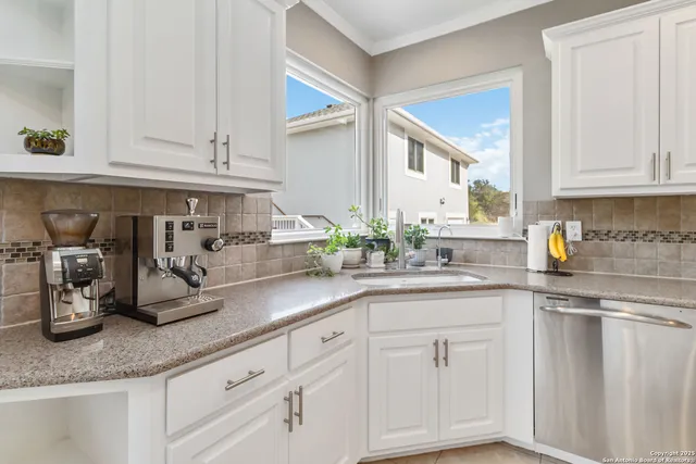 a kitchen with white cabinets and sink