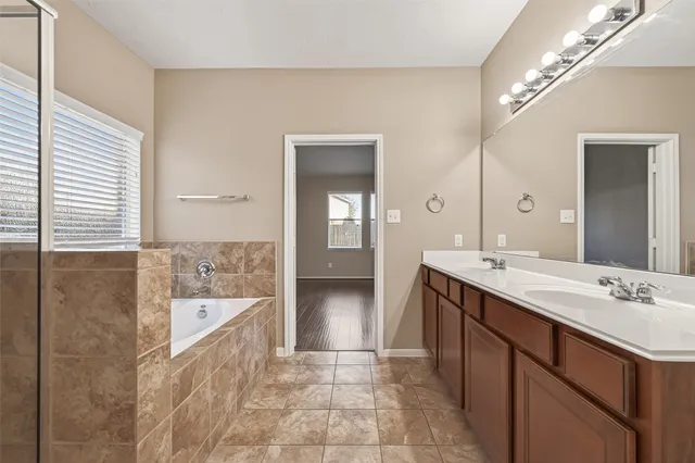 a bathroom with a double vanity sink mirror and bathtub