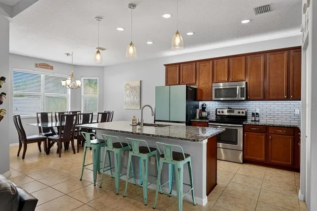 a kitchen with stainless steel appliances granite countertop a stove top oven a sink dishwasher a dining table and chairs