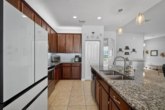 a kitchen with stainless steel appliances granite countertop a sink refrigerator and cabinets