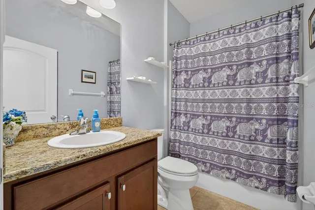 a bathroom with a granite countertop sink a toilet and shower