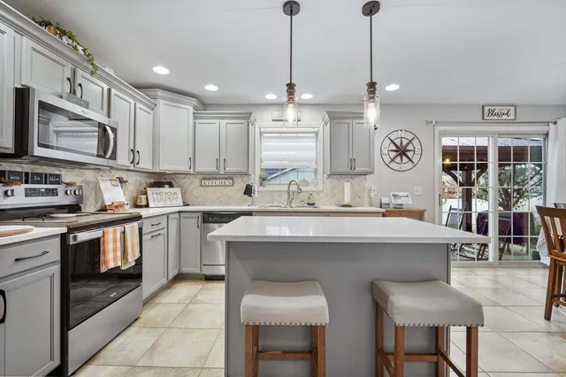 a kitchen with stainless steel appliances granite countertop a sink a stove a refrigerator and island