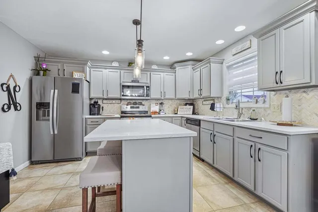 a kitchen with stainless steel appliances kitchen island a refrigerator sink and cabinets