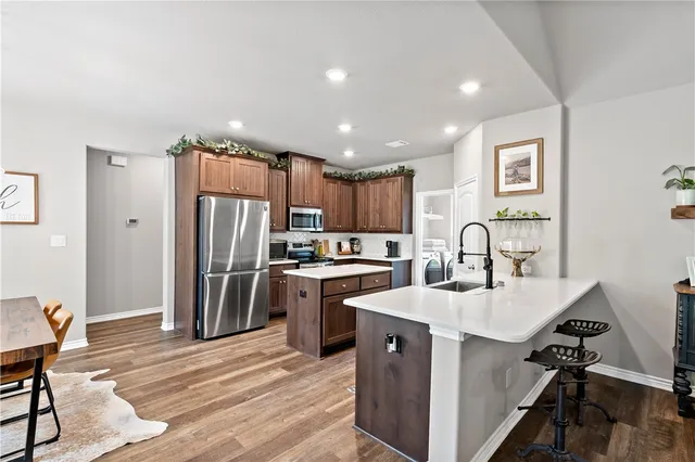 a kitchen with stainless steel appliances kitchen island a table chairs refrigerator and sink