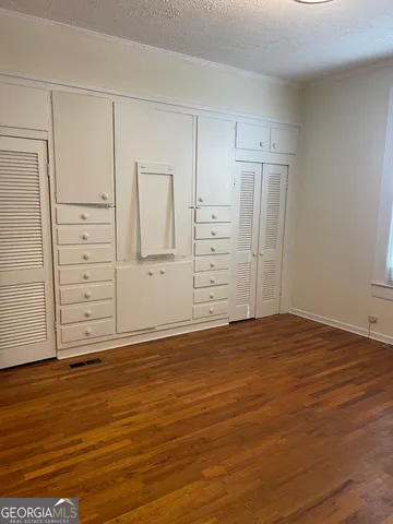 an empty room with chandelier fan and windows