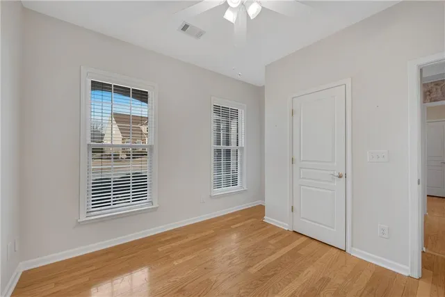 a view of an empty room with a window and chandelier fan