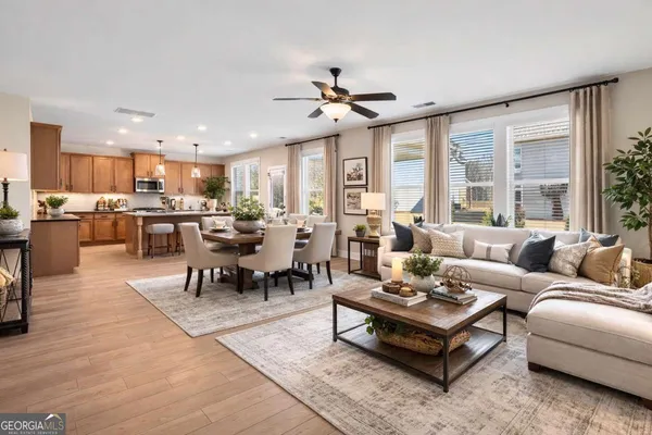 a living room with furniture kitchen view and a large window