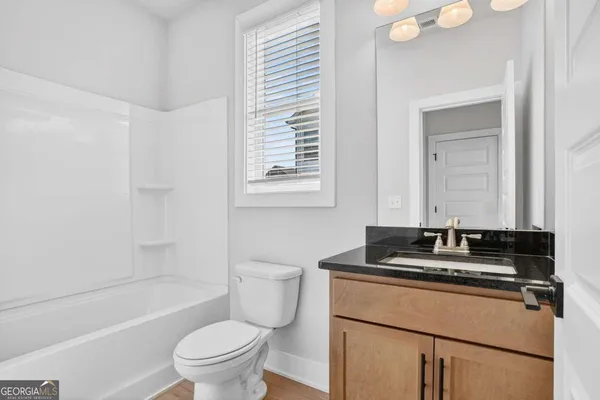 a bathroom with a granite countertop sink a toilet a mirror and shower