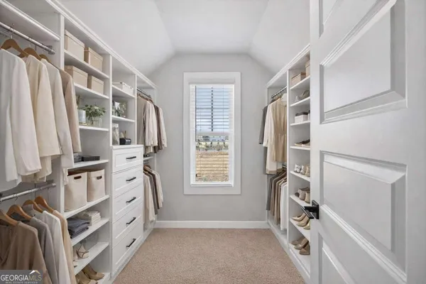 a view of walk in closet with clothes and shoes