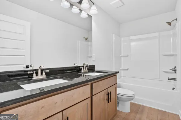 a bathroom with a granite countertop sink a toilet a mirror and bathtub