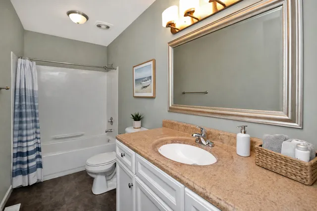 a bathroom with a granite countertop sink mirror vanity and toilet