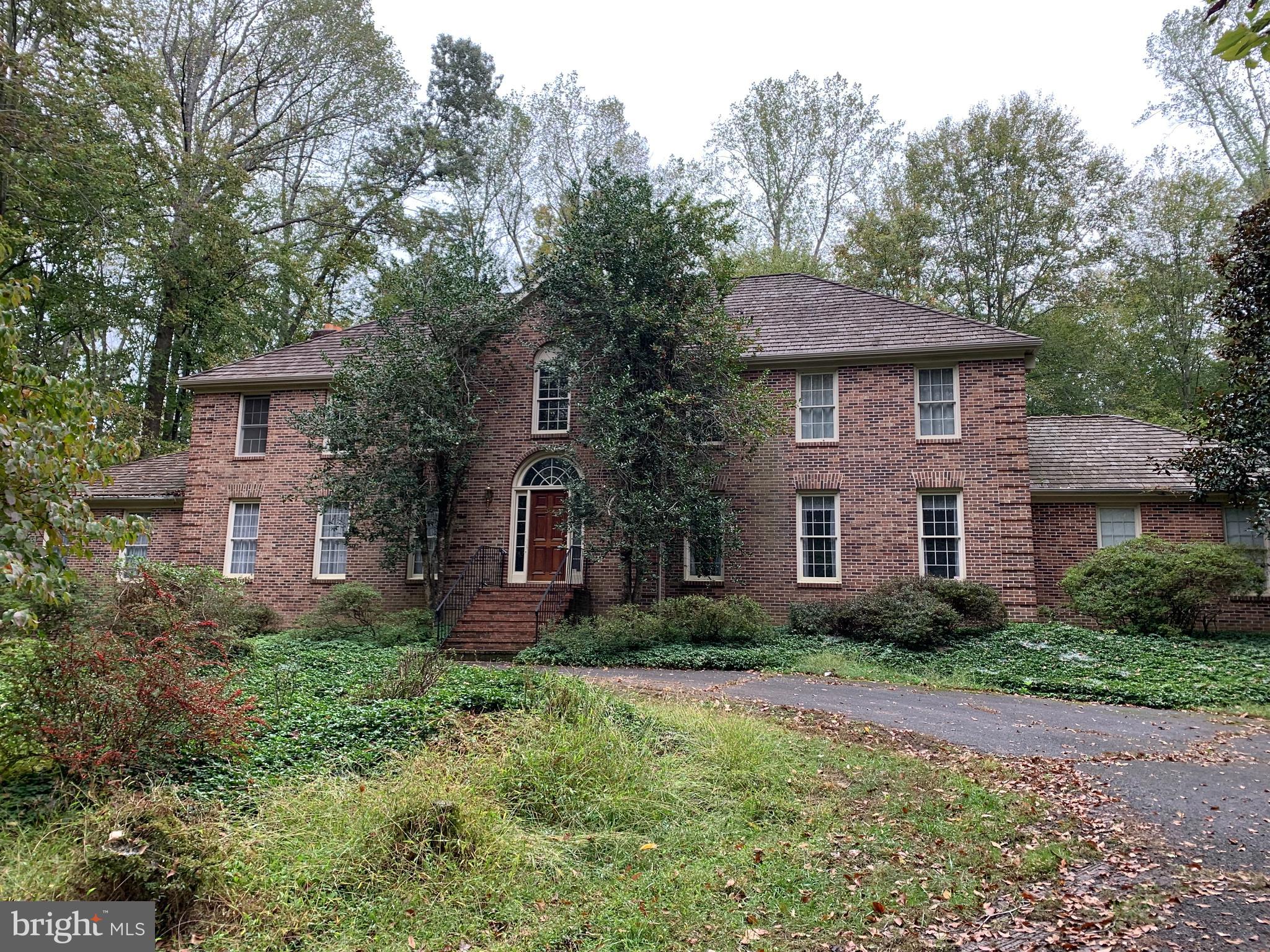 a brick house with small yard plants and large tree