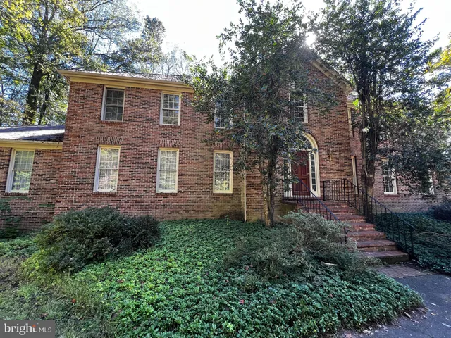 a brick house with a small yard and large trees