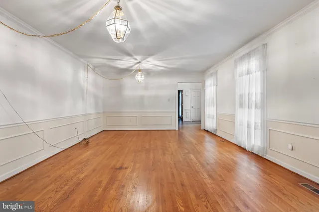a view of an empty room with wooden floor and fan