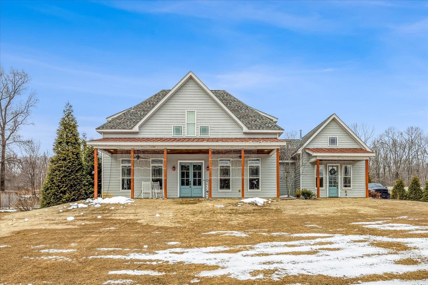View of front facade with french doors, covered porch, and a shingled roof