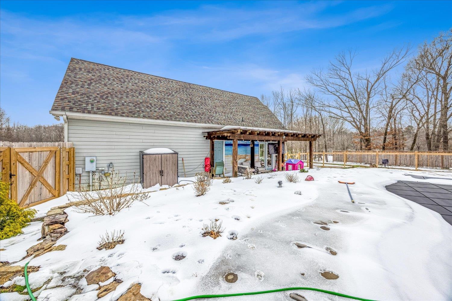 897 Burrowtown Road Mason, TN 38049 - Photo 31 of 36 Yard layered in snow featuring a pergola, a fenced backyard, a gate, and a patio