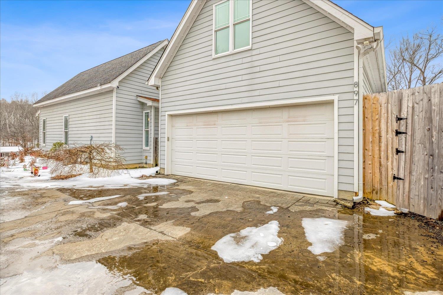 897 Burrowtown Road Mason, TN 38049 - Photo 32 of 36 View of snowy exterior with a garage, roof with shingles, driveway, and a gate