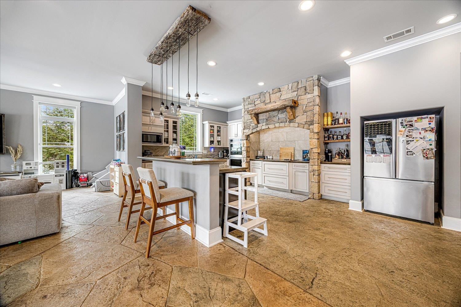 897 Burrowtown Road Mason, TN 38049 - Photo 7 of 36 Kitchen with a breakfast bar, stone tile floors, stainless steel appliances, dark countertops, and hanging light fixtures
