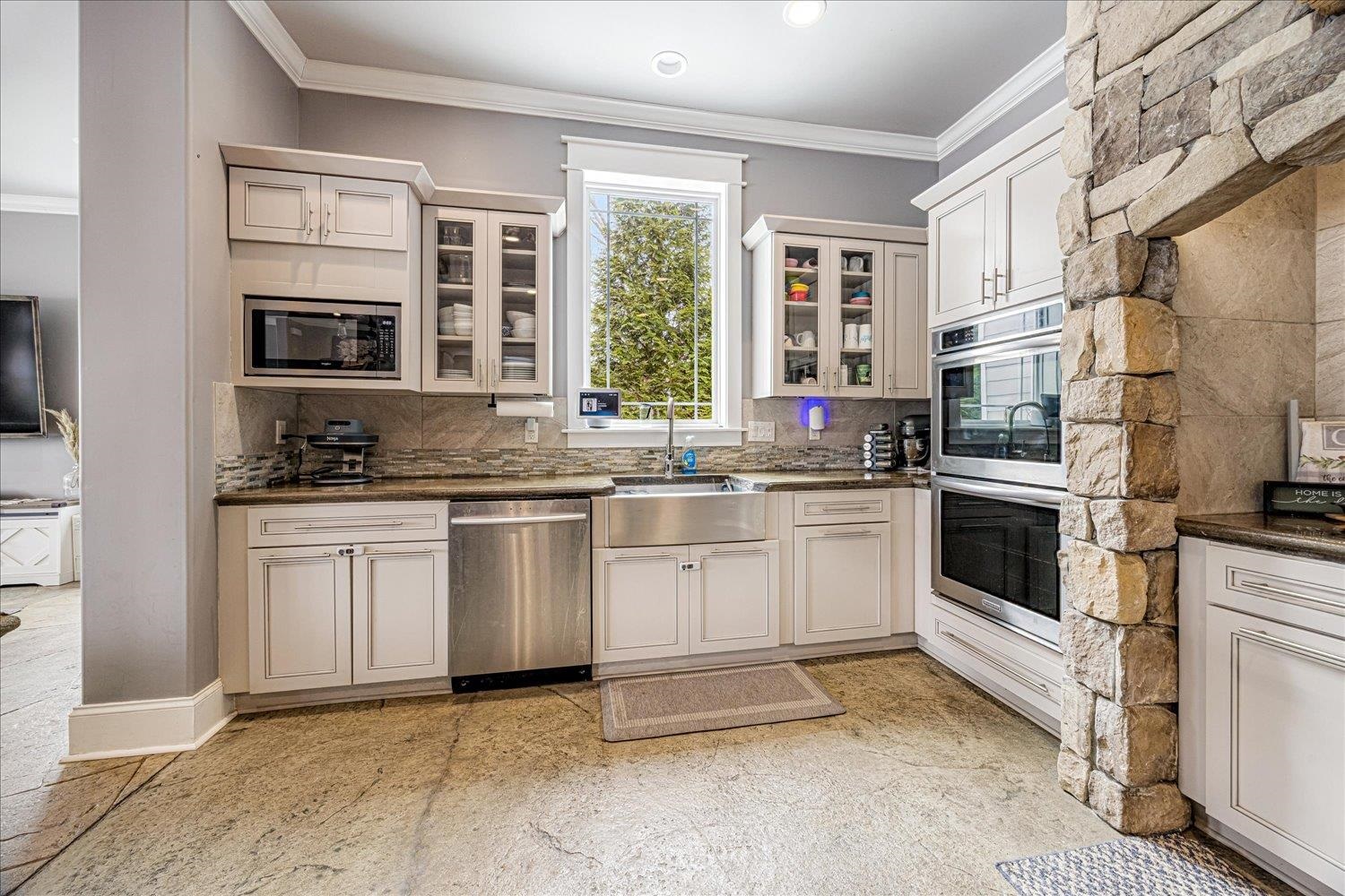 897 Burrowtown Road Mason, TN 38049 - Photo 8 of 36 Kitchen with ornamental molding, glass fronted cabinets, stainless steel appliances, dark stone counters, and white cabinetry
